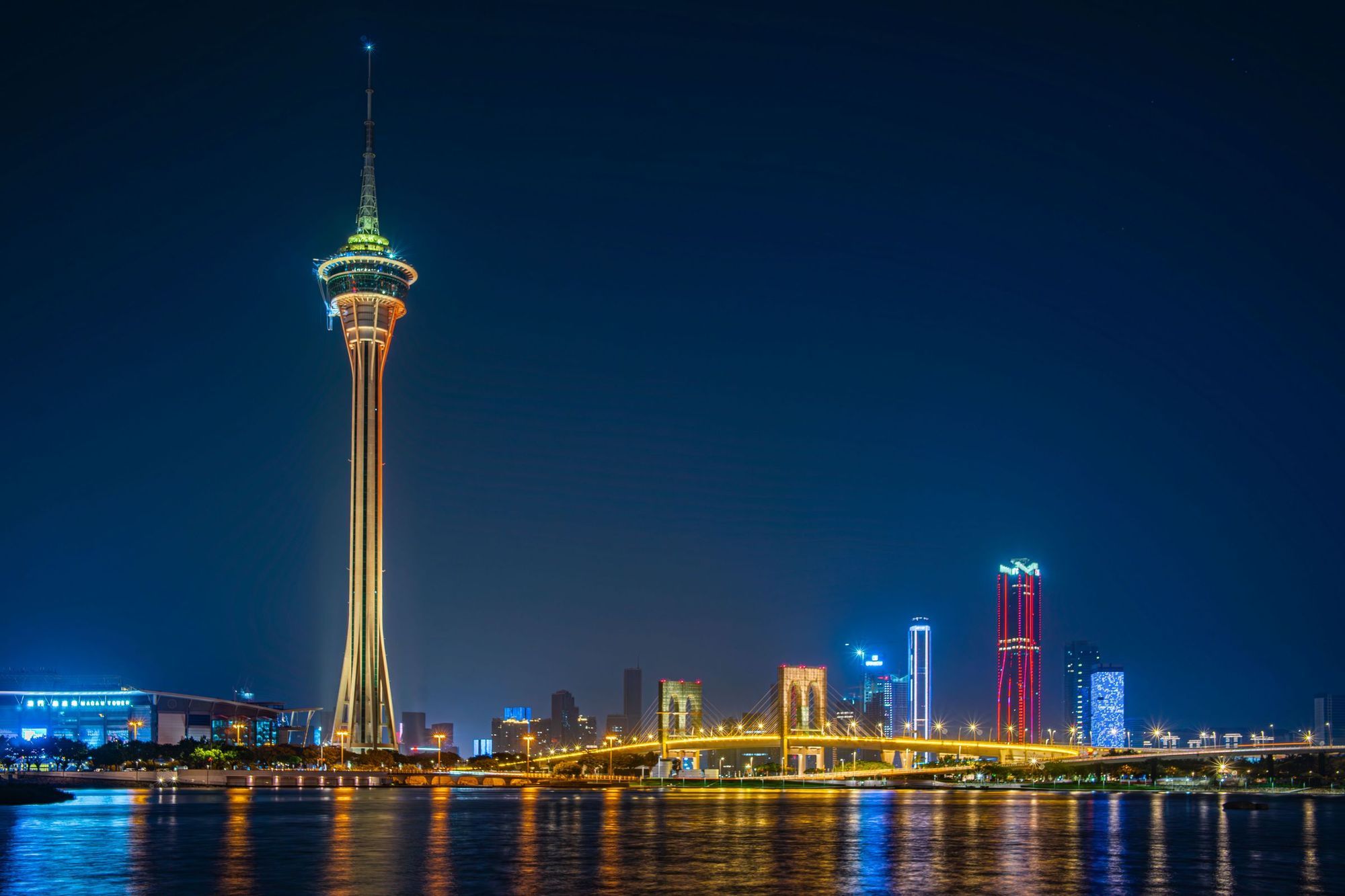 Macau Tower and the illuminated Macau skyline reflected in the water at night