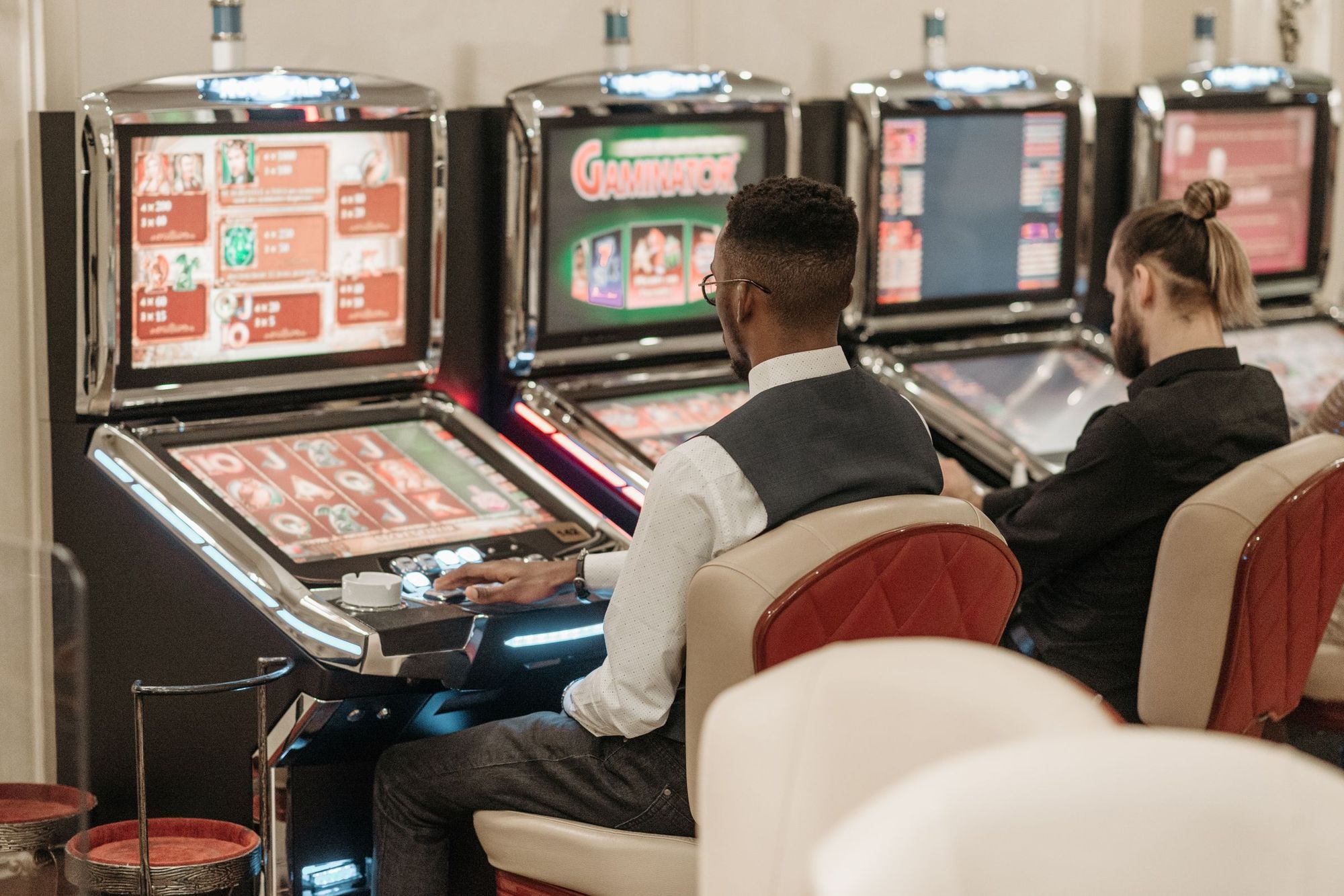 Two players seen from behind sitting at slot machines in a casino