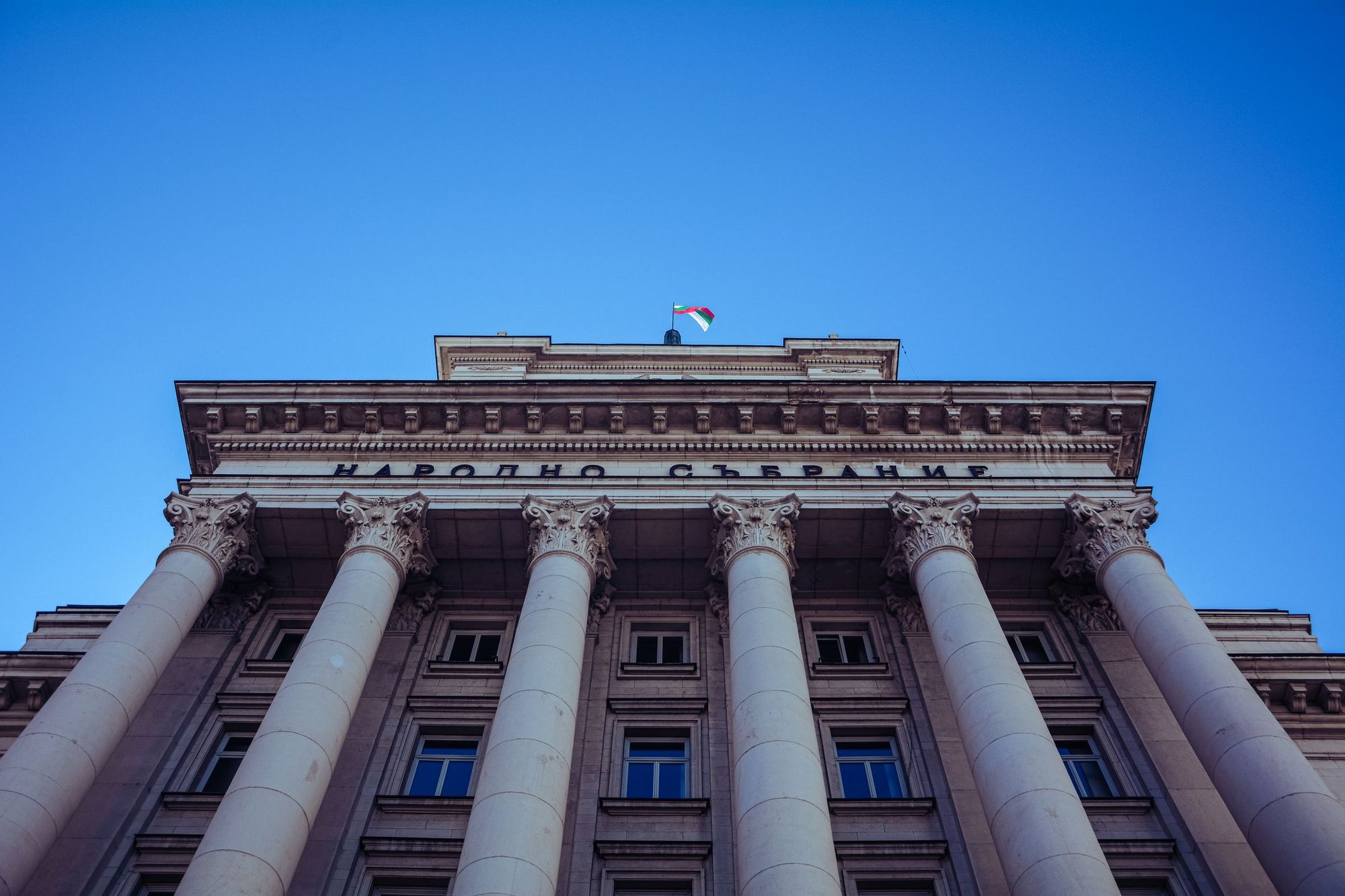 Low-angle view of the columns of the parliament building in Sofia under a clear blue sky